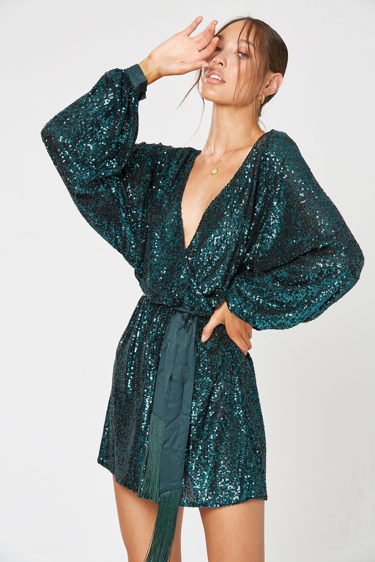Model wearing Winona Broadway emerald sequin wrap mini with tassel tie belt