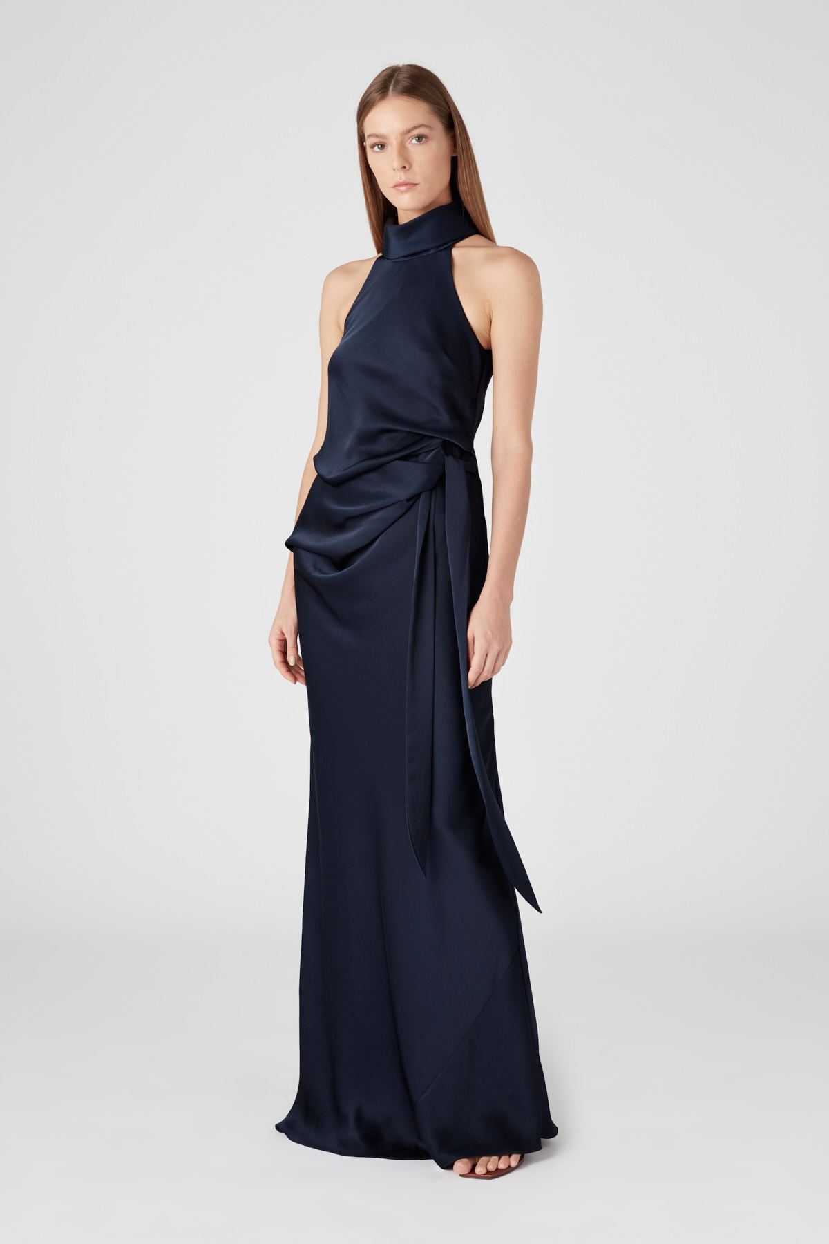 Model wearing Camilla and Marc Antonelli navy satin halter gown with waist tie