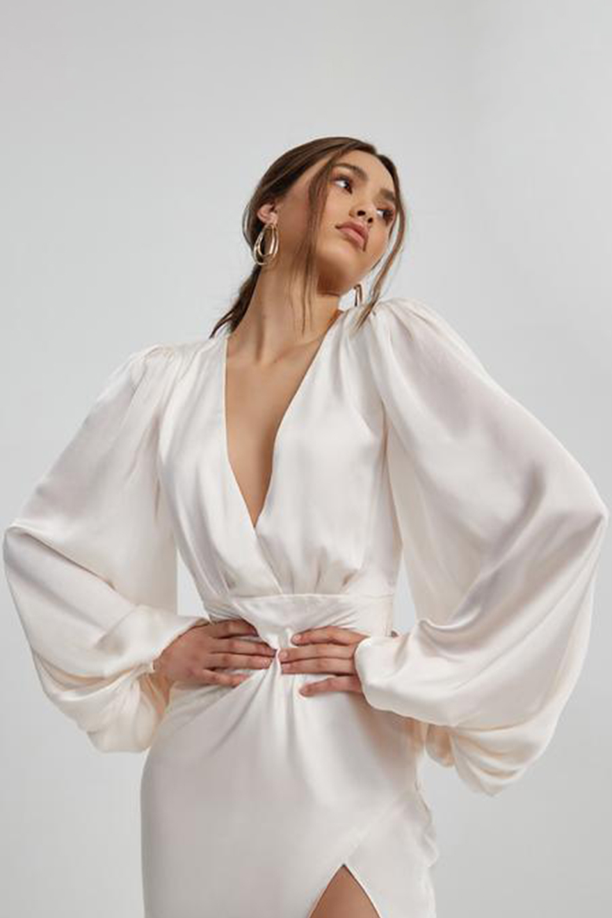 Model wearing Lexi India blush satin gown with billowing sleeves and thigh split