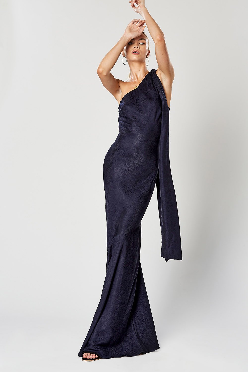 Model wearing Winona Virtue navy bias-cut one shoulder maxi with fluted hem